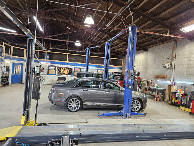 A car is sitting on a lift in a garage. | J & J Automotive