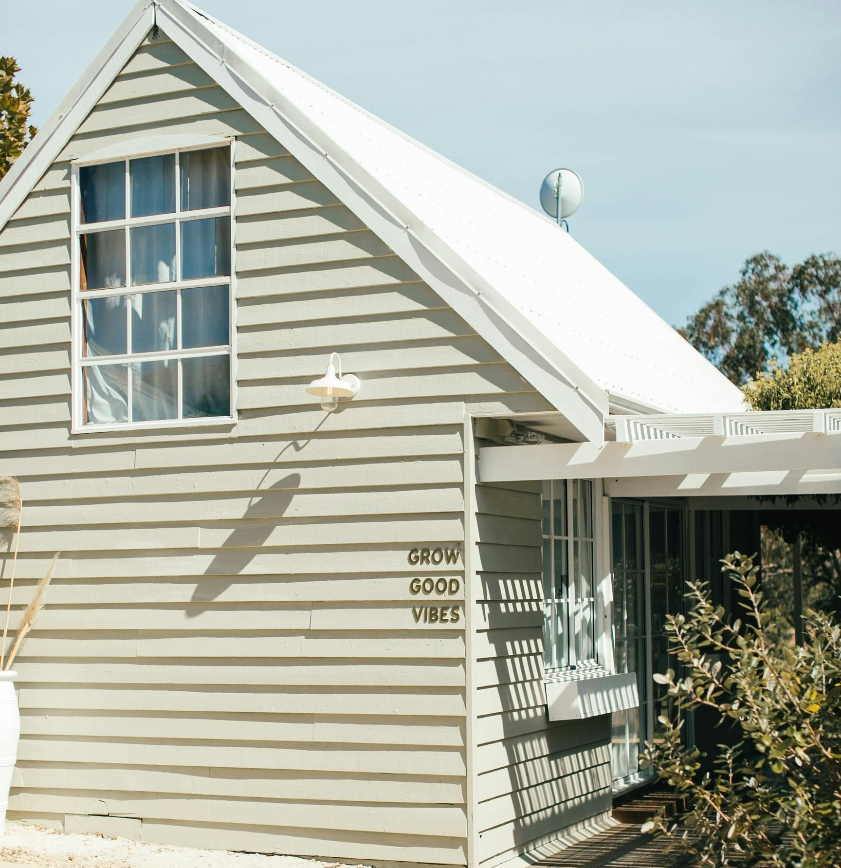Gray wooden cottage with white roof and a window;