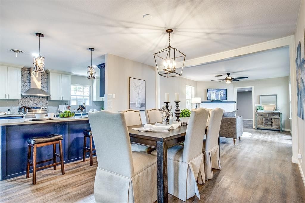 Bright open-concept dining and kitchen area with blue island, chandelier, and long dining table