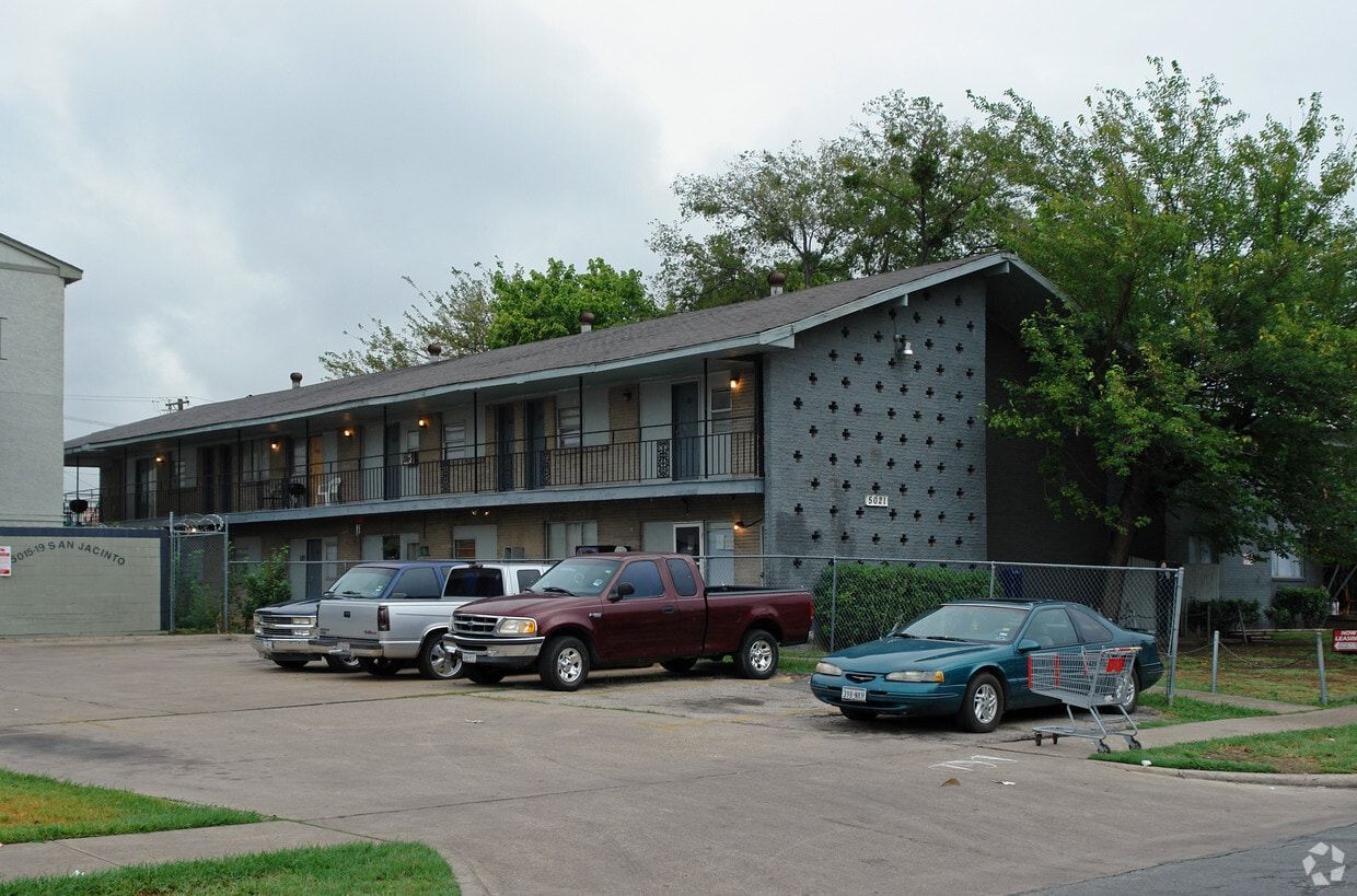 Two-story apartment building with parked cars in front on a cloudy day
