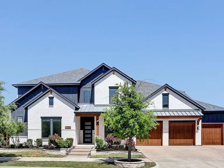 Modern gray suburban house with a three-car garage and a tree in front