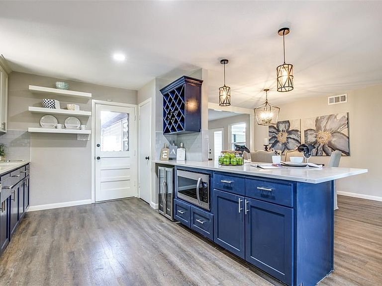 Modern kitchen with blue cabinets, white countertops, pendant lights, and wood-look flooring