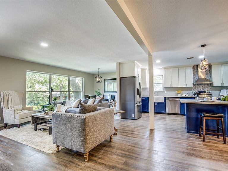 Bright open-concept living room with gray sofa, wood floors, and blue kitchen island