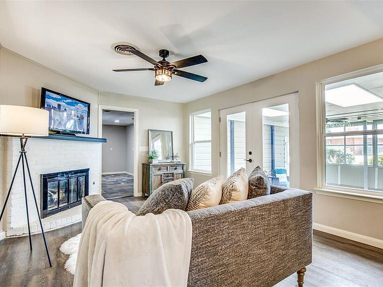 Bright living room with gray sofa, fireplace, ceiling fan, and sliding glass doors to a screened patio
