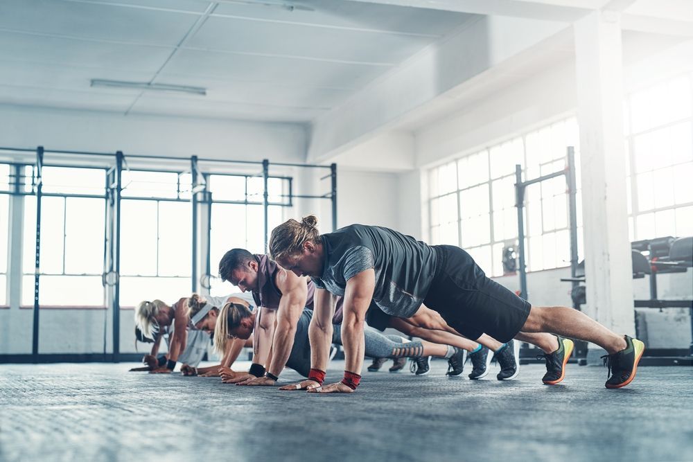 People doing push-ups in a bright gym class with large windows