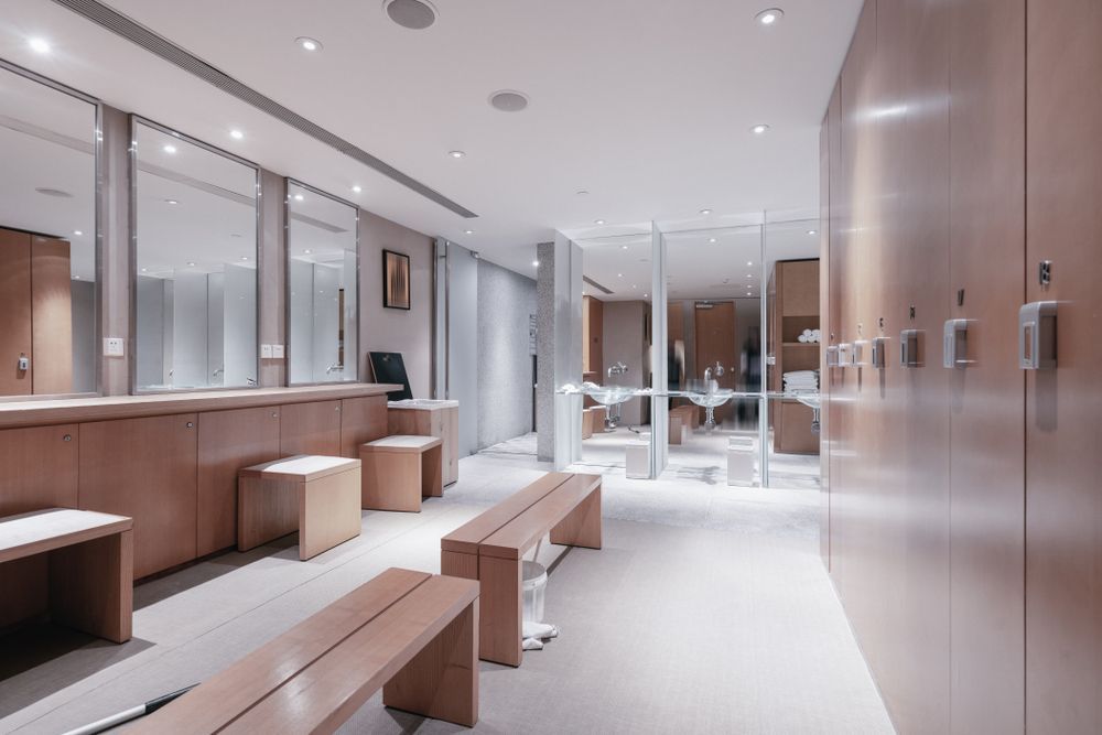 Modern locker room with wooden benches, mirrors, and glass showers in a clean, bright interior