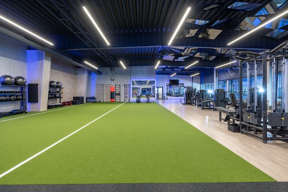 Modern indoor gym with turf track, weight machines, and blue accent lighting