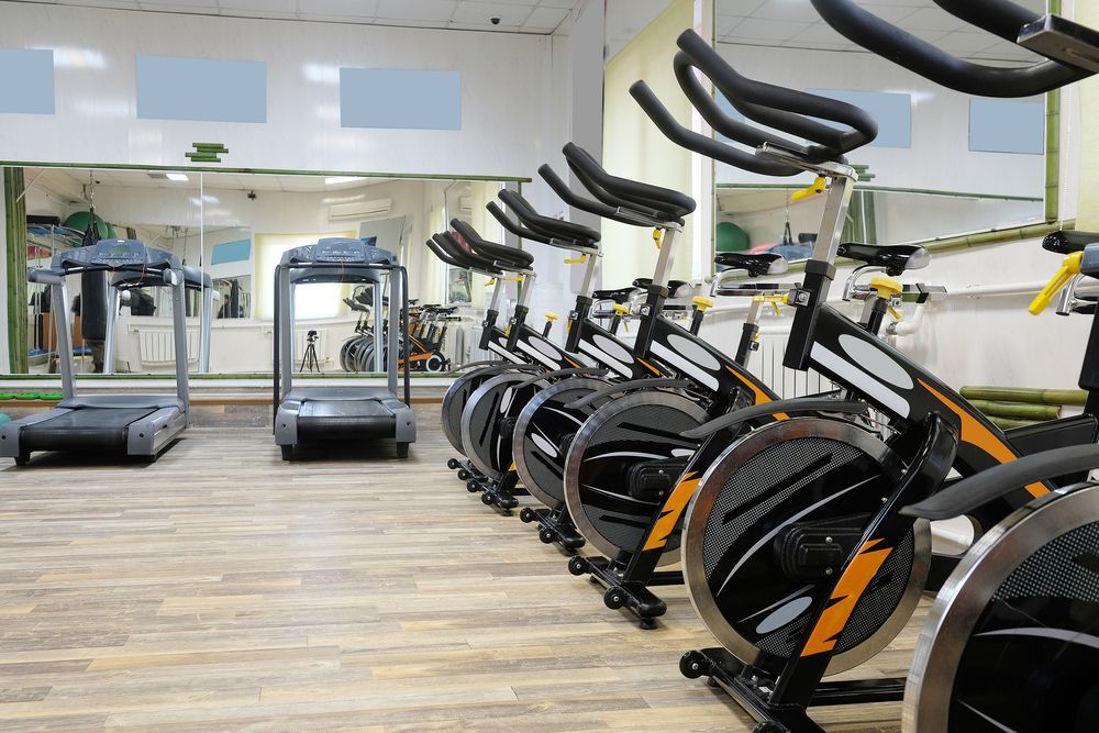 Modern gym with treadmills and stationary bikes in a bright mirrored room