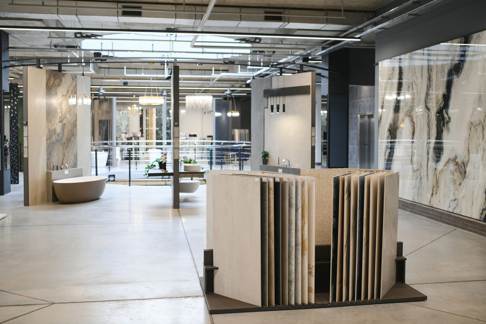 Modern showroom with tile displays, large marble slabs, and open industrial interior.