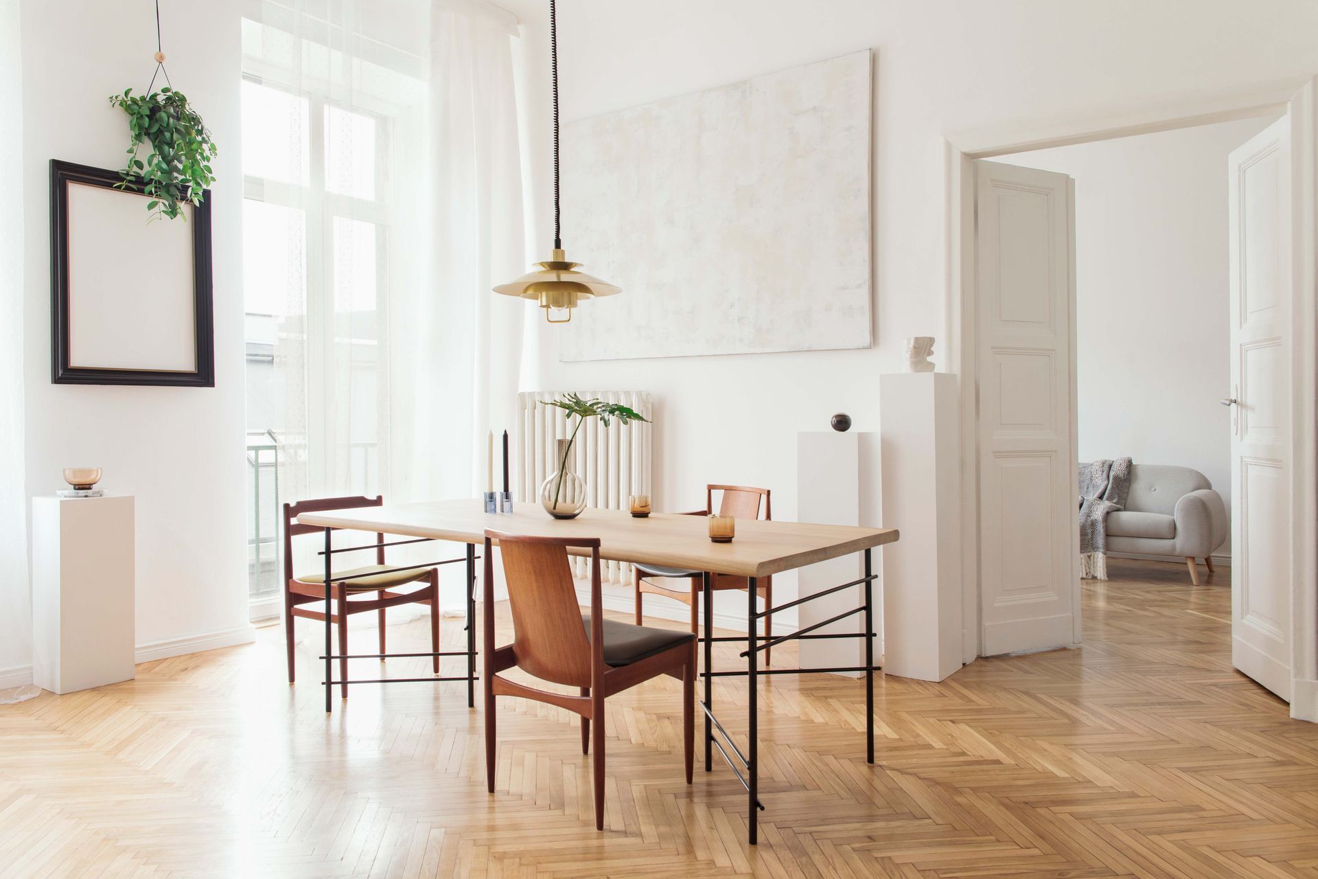 Bright dining room with wooden table and chairs, large windows, white walls, and a hanging pendant light