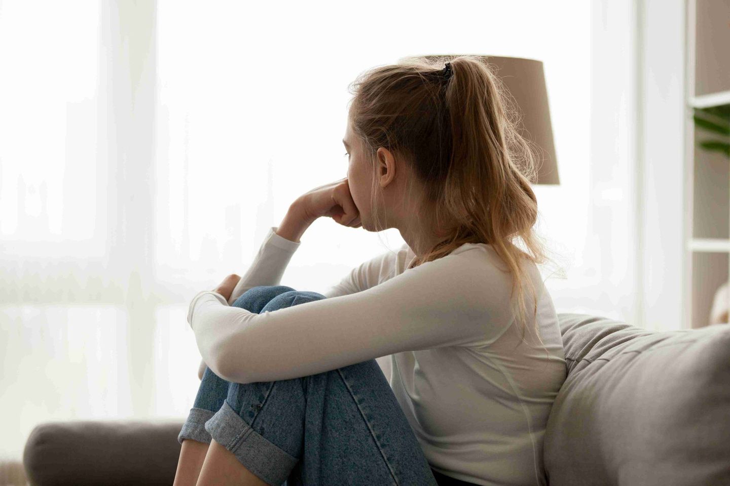 Sad woman alone in her room looking at the window