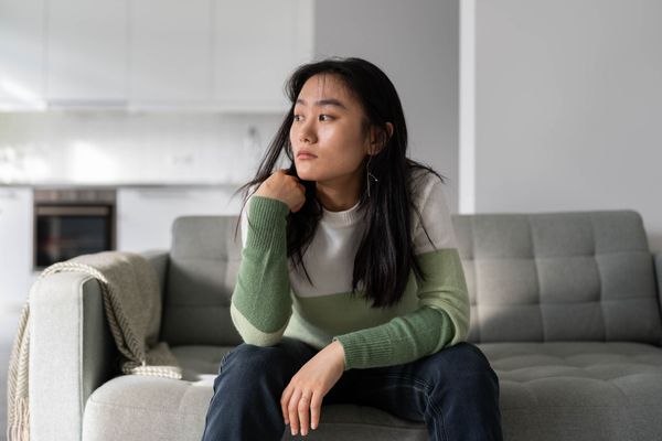 Woman with hands clasped under chin, looking thoughtful.