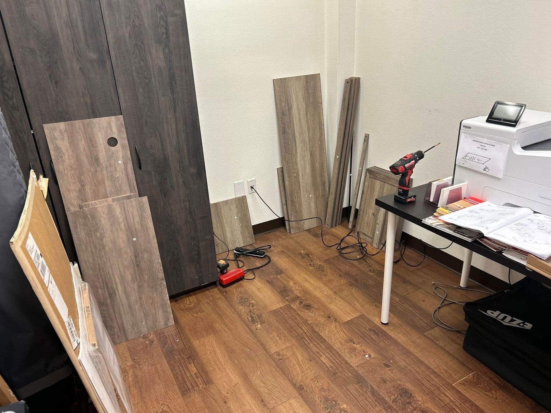Room with wood furniture parts, tools, and a desk; assembly in progress.