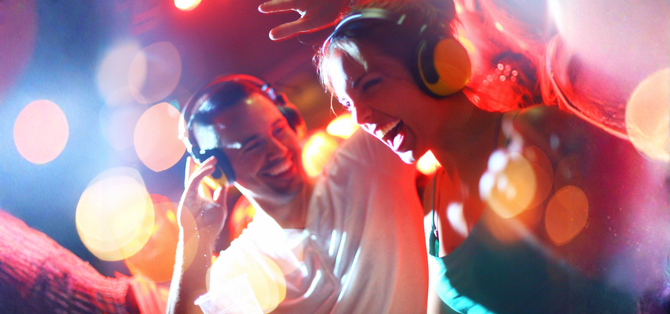 Folla che balla a una festa notturna all'aperto con luci colorate e palco musicale