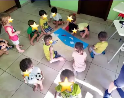 I bambini siedono in cerchio attorno a un tappeto blu, giocando insieme in un'aula piastrellata.