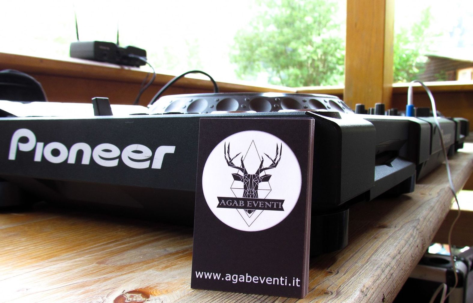 Apparecchiature audio Pioneer su un tavolo di legno con un cartellino nero con il logo davanti e una finestra luminosa dietro.