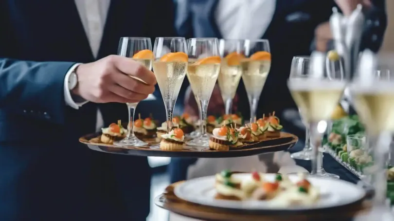 Cameriere che serve antipasti e flûte di champagne a un tavolo di ricevimento formale