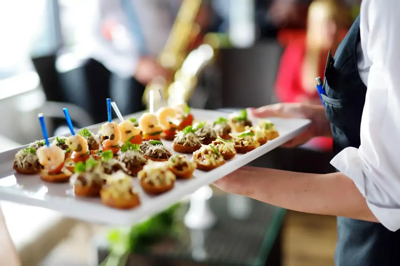 Vassoio di antipasti assortiti con stuzzicadenti, portato da un cameriere durante un evento con servizio di catering.