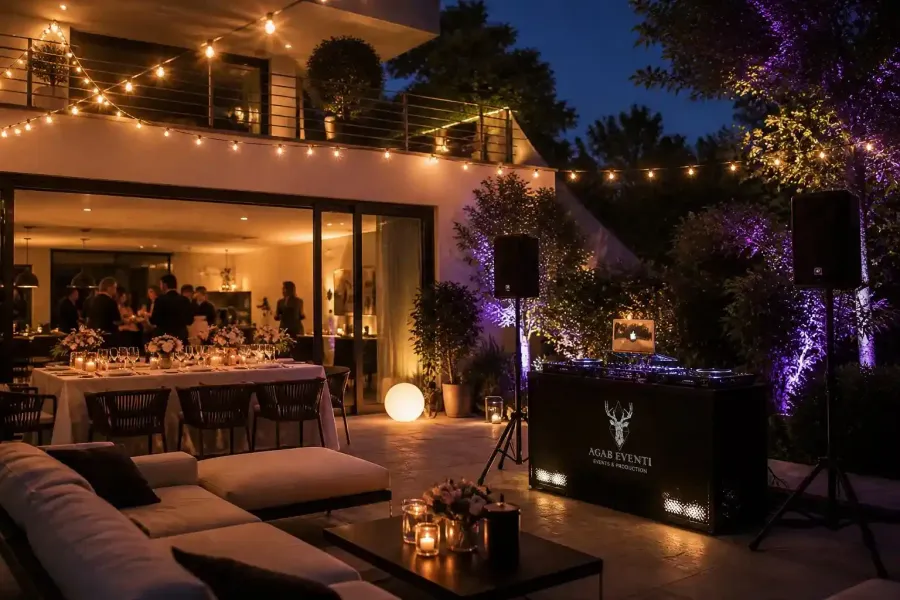 Elegante patio esterno al crepuscolo con luci decorative, comode poltrone e una zona pranzo illuminata da una luce calda.