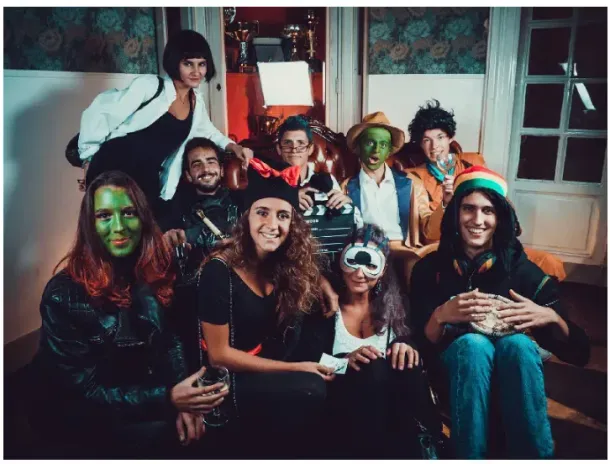 Un gruppo di amici in costume di Halloween posa su un divano, con i volti dipinti ed espressioni giocose.