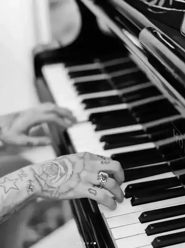 Mani tatuate che suonano una tastiera di pianoforte in bianco e nero