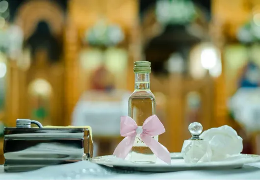 Tavolo da pranzo decorato con una bottiglia, un tovagliolo e un piatto coperto con nastro rosa, in un ambiente da ristorante.