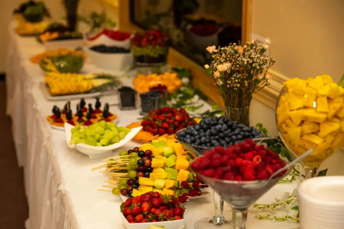 Buffet di frutta con fragole, mirtilli, ananas e altra frutta su un tavolo all'interno