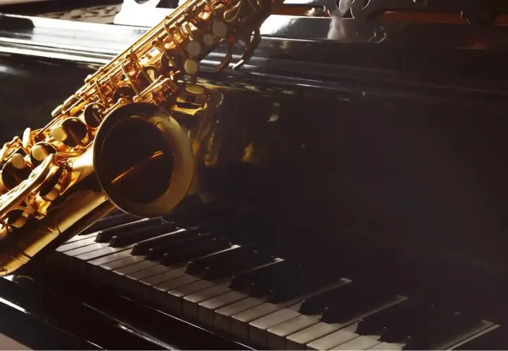 Sassofono dorato appoggiato sui tasti del pianoforte in una luce calda
