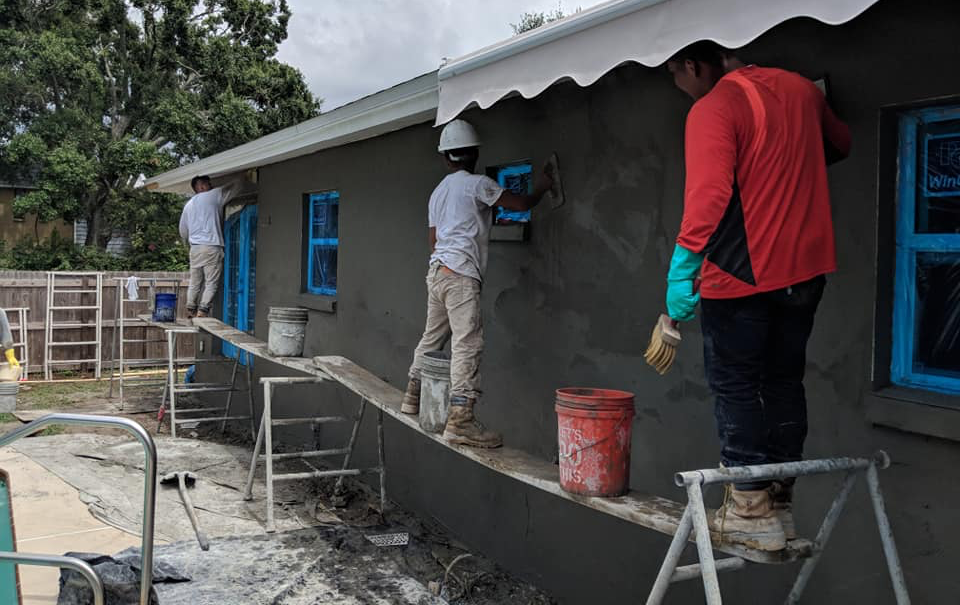 A group of construction workers are painting a house.