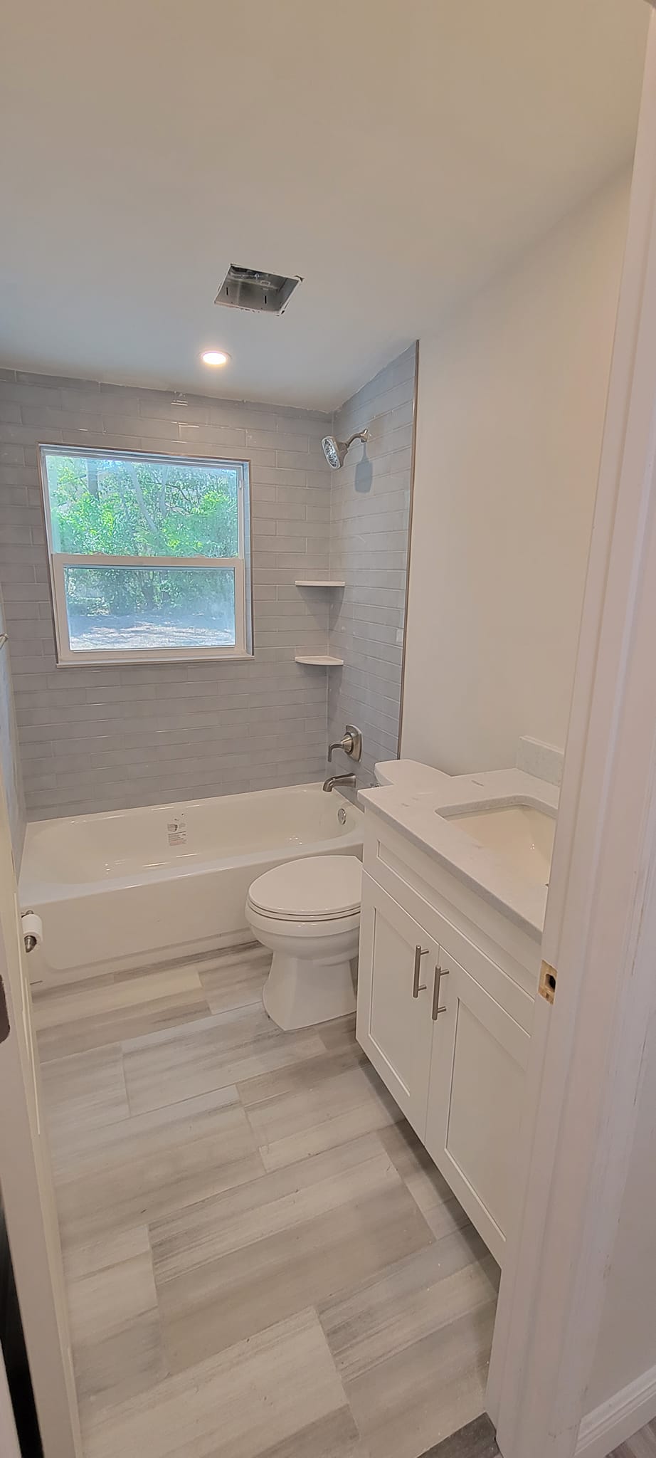 A bathroom with a sink , toilet , tub and window.