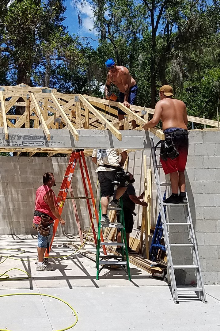 A group of construction workers are working on the roof of a house.