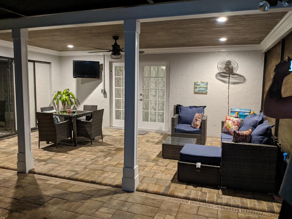 A patio with a dining table , chairs , and a television.