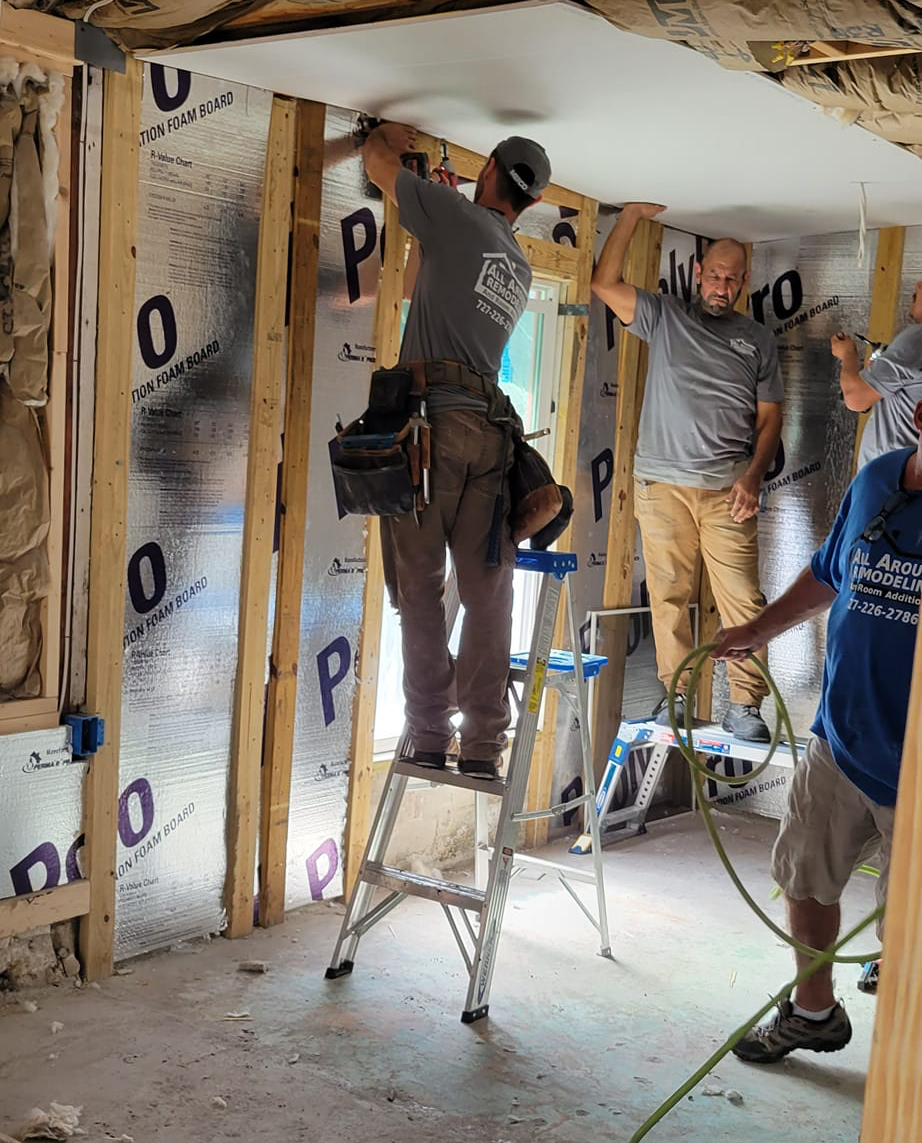 A group of men are working on a ceiling in a room.