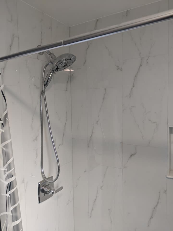 A shower head is hanging from a shower curtain in a bathroom.
