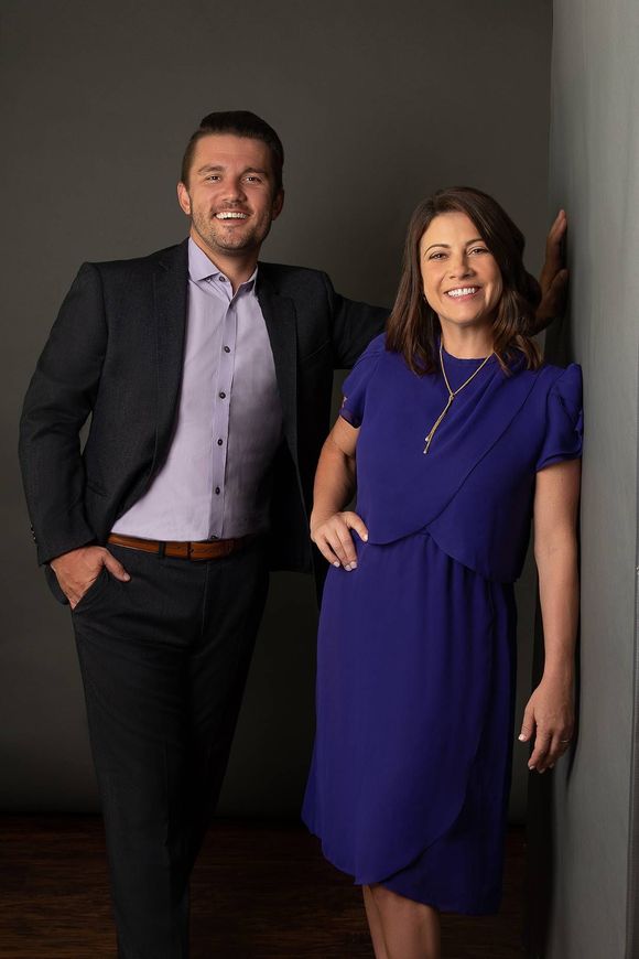 A man in a suit and a woman in a blue dress are standing next to each other.