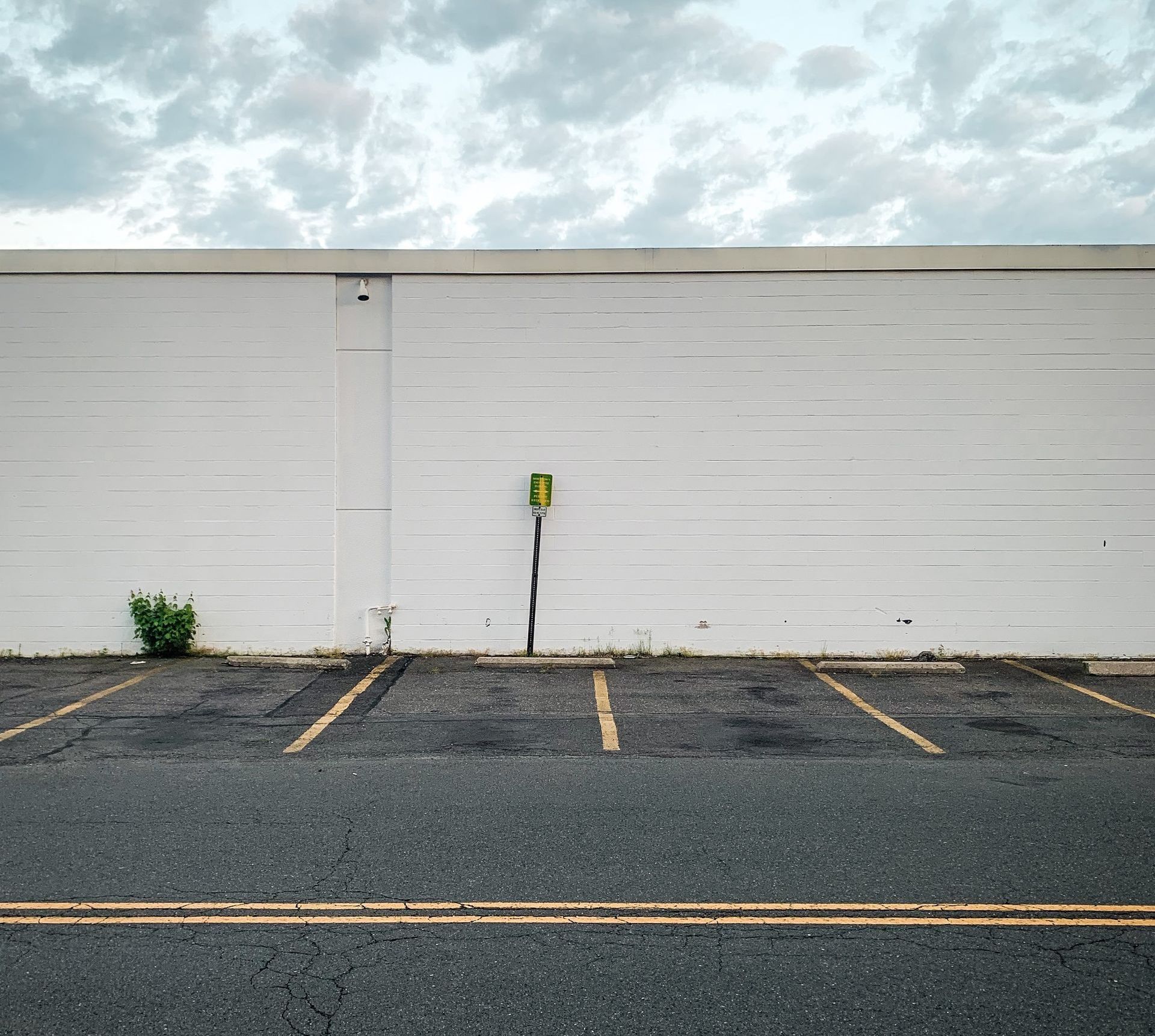 An empty parking lot with a white wall in the background.