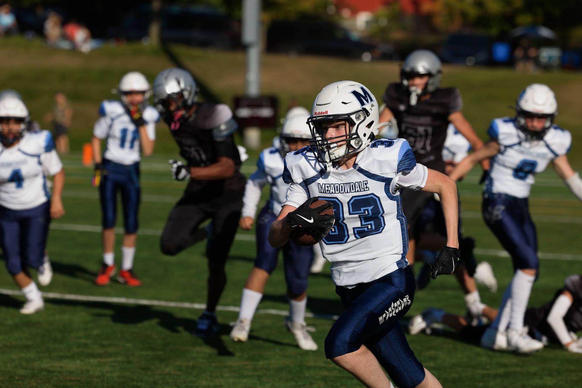 Youth football player in blue and white running with the ball on a sunny field