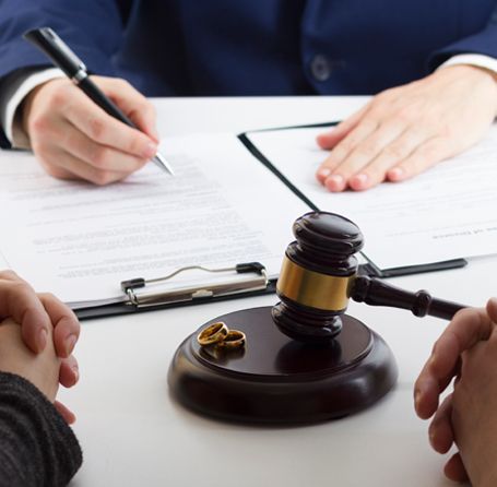 Divorce proceeding: Wedding rings, gavel, legal documents, hands, and person writing. Divorce proceeding: Wedding rings, gavel, legal documents, hands, and person writing.