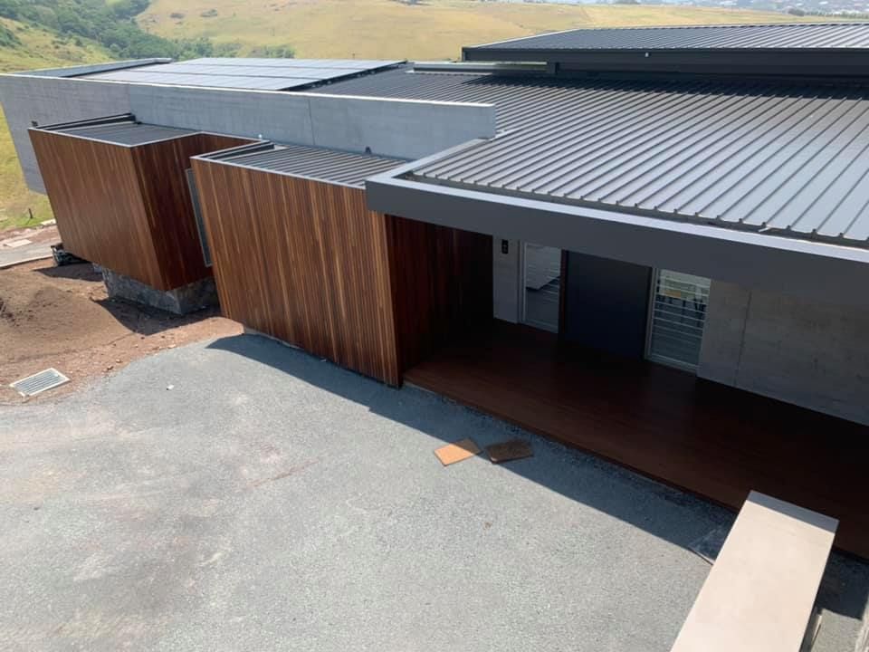 Modern building with corrugated metal roof and wood-paneled walls. Exterior view with paved driveway.