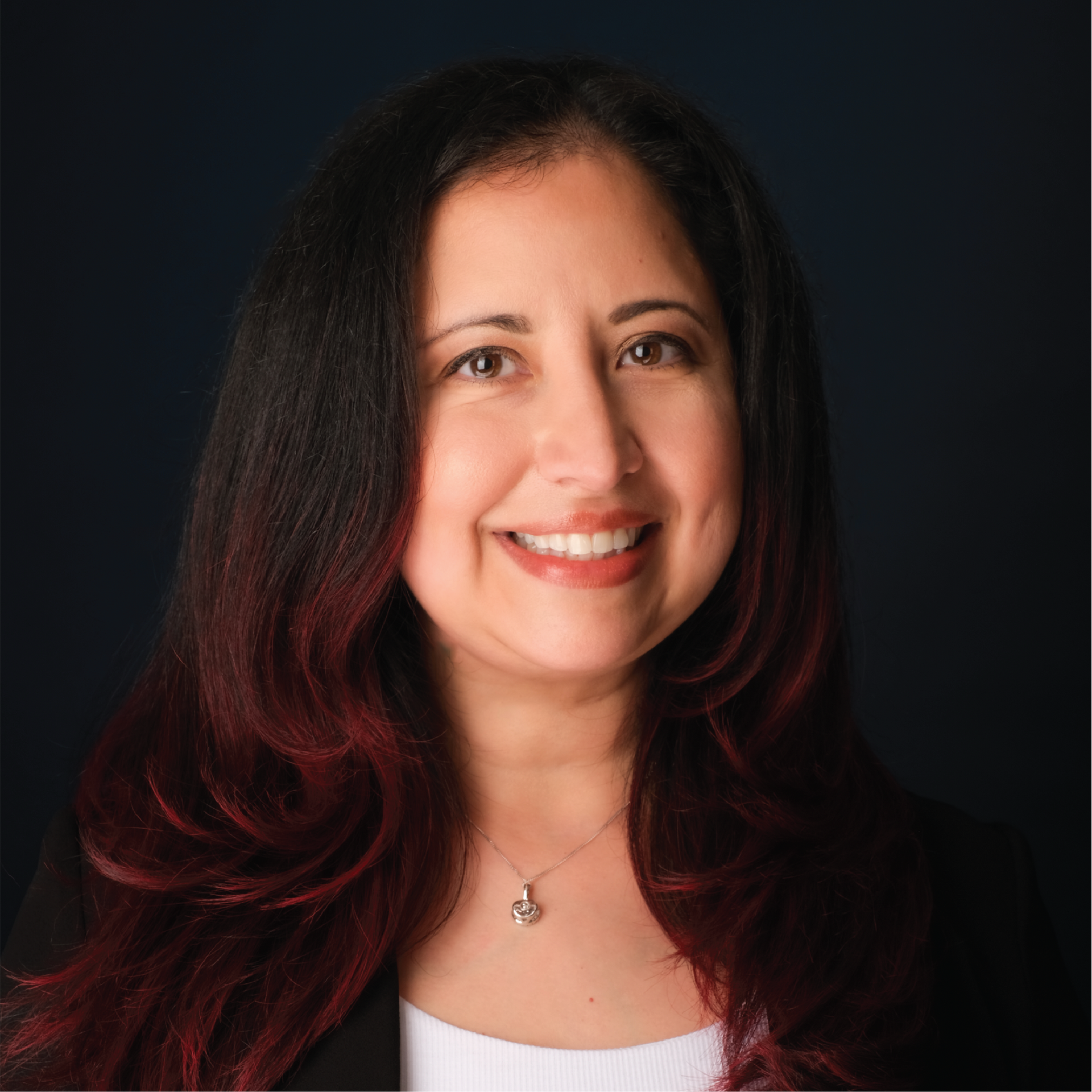 Smiling woman with red hair in a white top against a gray studio backdrop