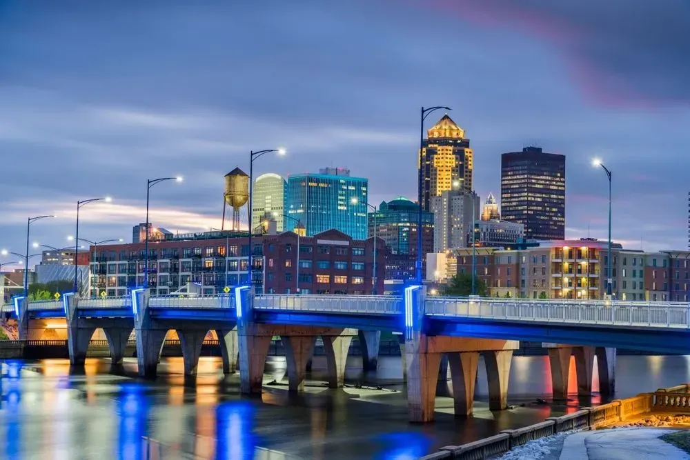 City skyline at dusk with a lit bridge reflected on calm water