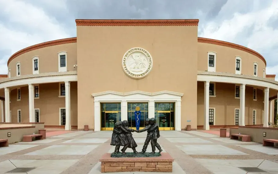 Clock-topped building with arched facade and a bronze statue in front under a clear sky