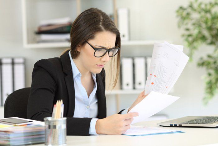 Person in glasses reviewing documents at a desk in an office