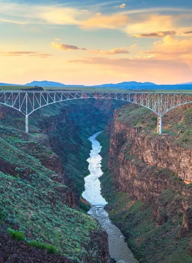 Bridge over a deep canyon with a river below at sunset