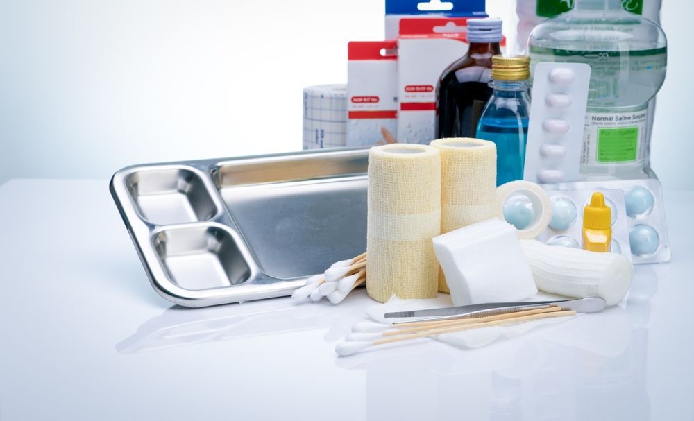Assorted first aid and medical supplies on a white surface, including bandages, gauze, and bottles