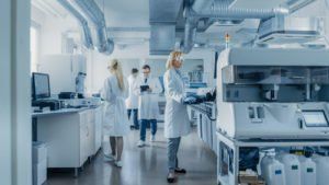 Scientists working in a bright laboratory with lab equipment and computers