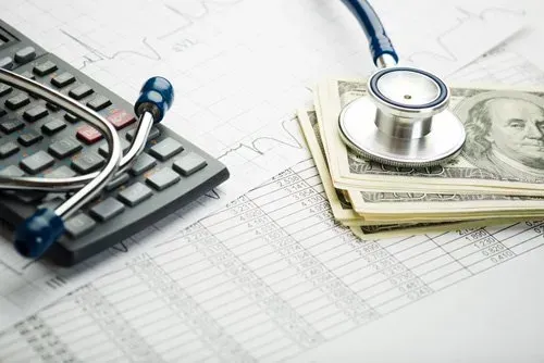 Calculator, stethoscope, and cash on a financial chart, suggesting healthcare costs or budgeting