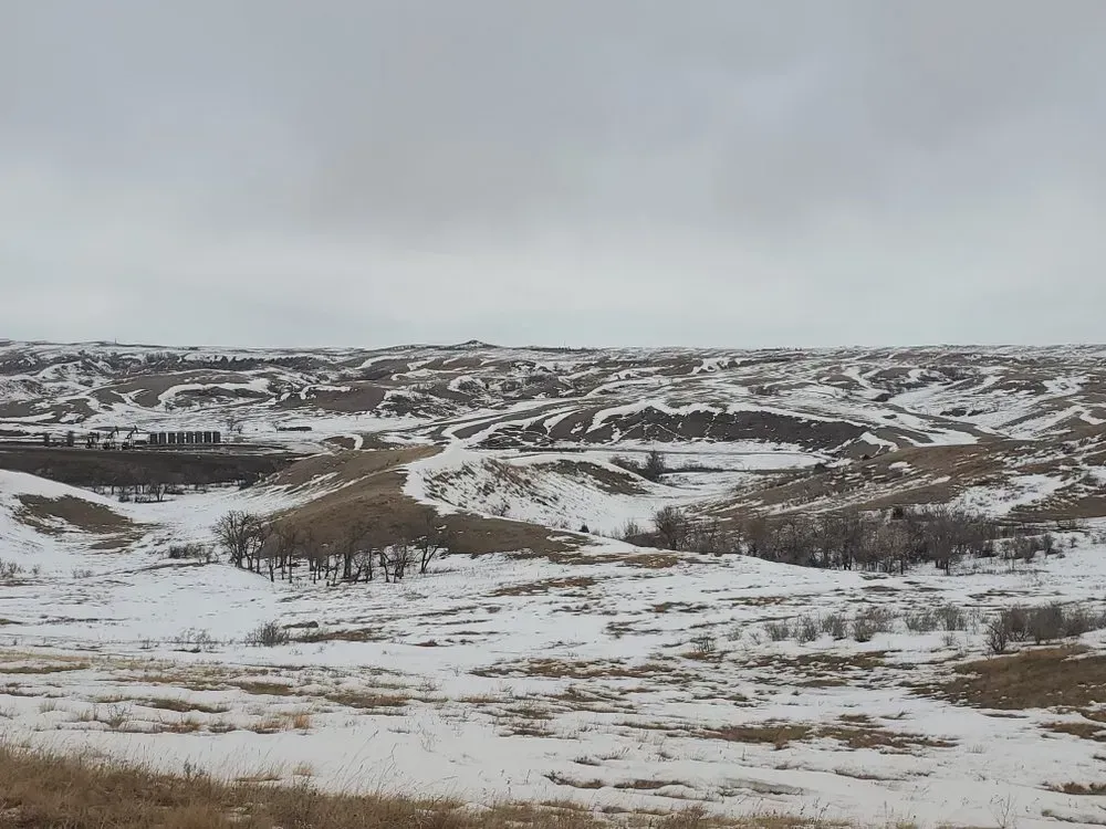 Snow-covered rolling hills under a cloudy sky.