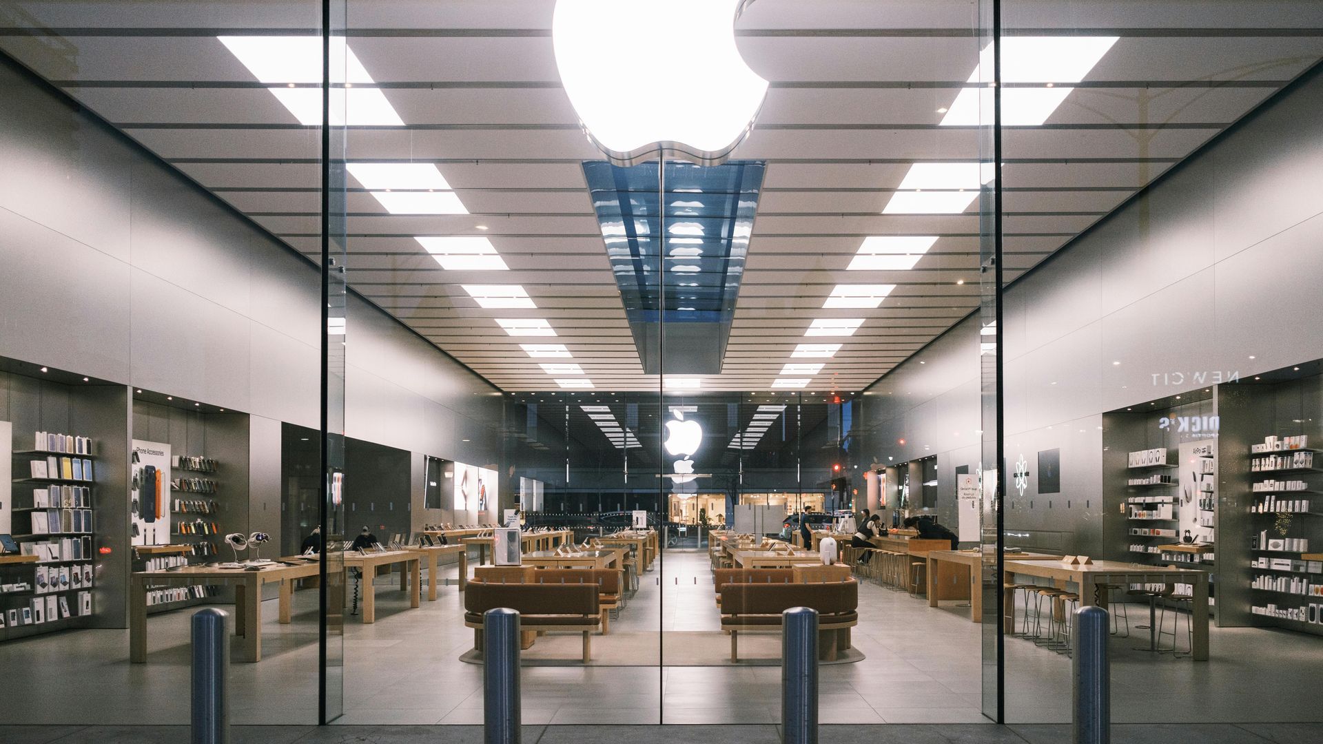 Modern bookstore interior with glass entrance, shelves, tables, and a central aisle under bright lights