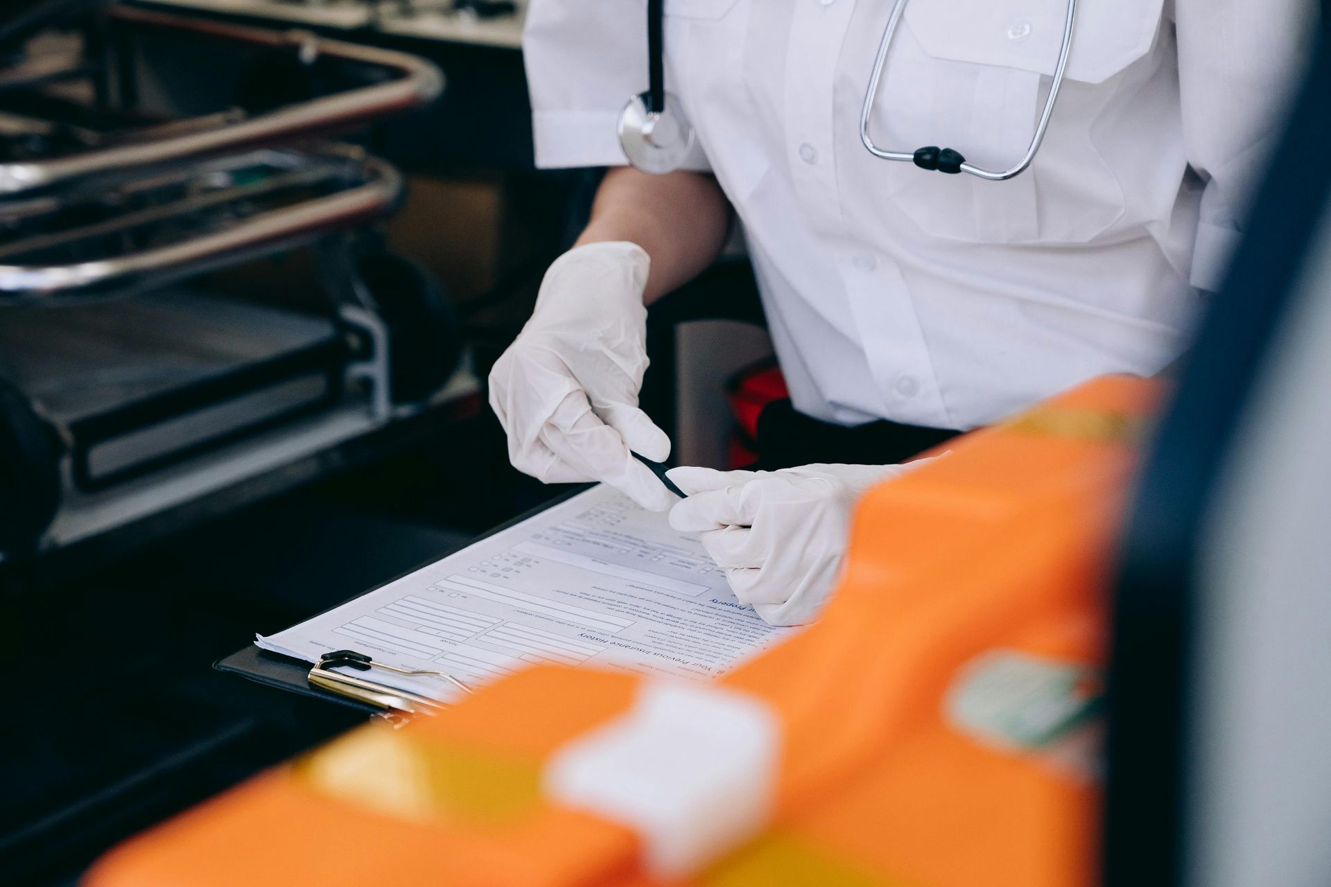 Gloved worker writing on a checklist beside orange safety gear in a vehicle or workshop